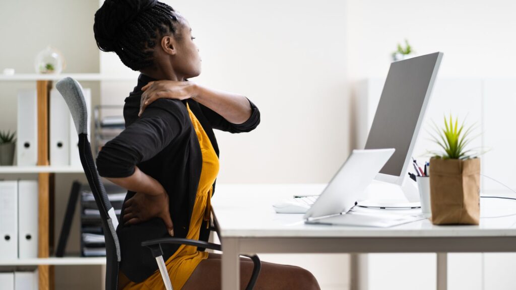 Office worker with a sore shoulder (RSI) from a poorly designed workstation.